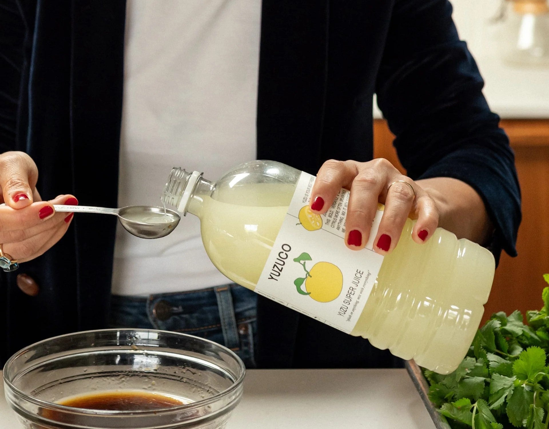 Yuzu juice being poured into a glass bowl with soy sauce, highlighting its use as a bright citrus enhancer.