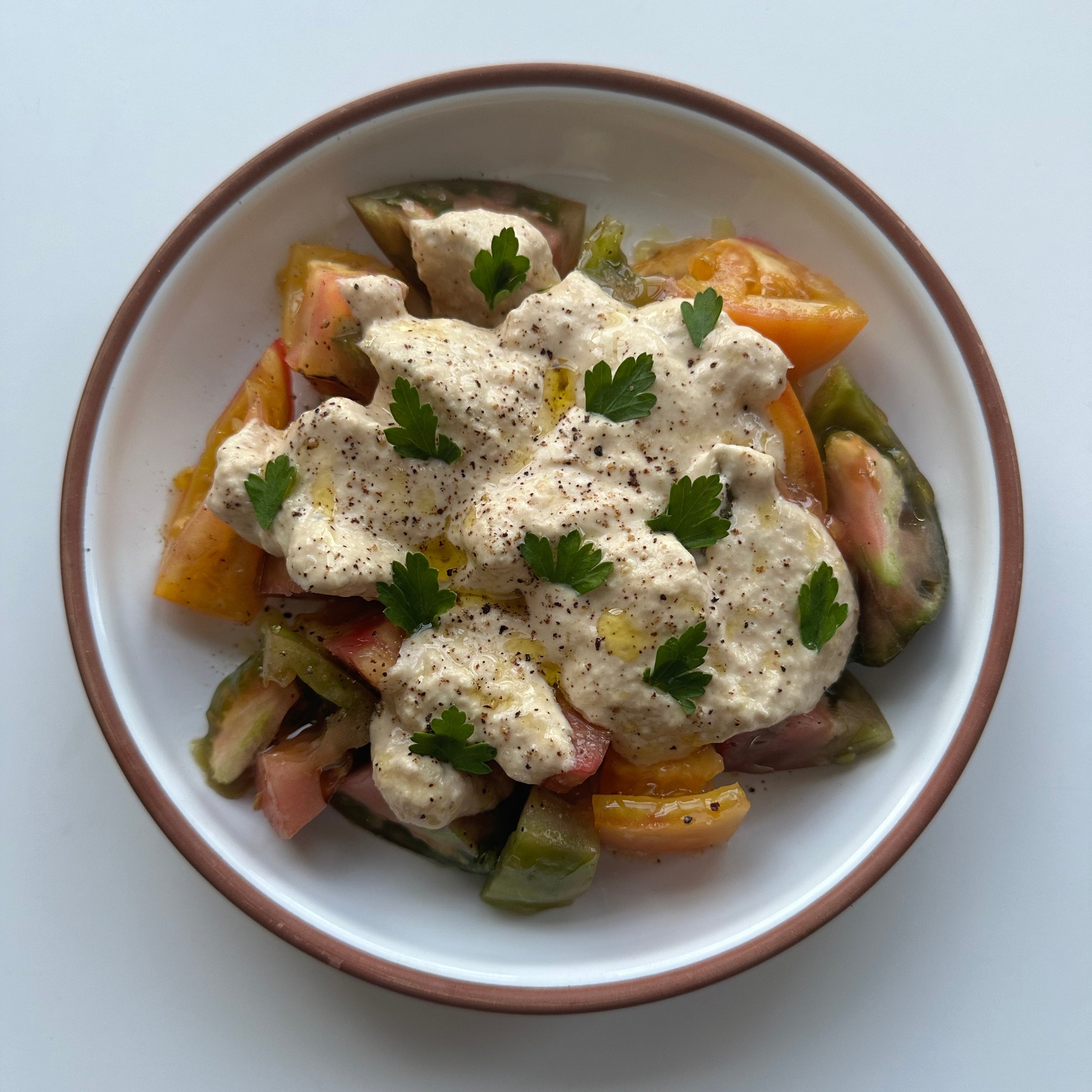 Top-down of Tomato Tonnato (Sudachi) with chopped heirloom tomatoes, creamy tonnato sauce, cracked black pepper, parsley, and olive oil