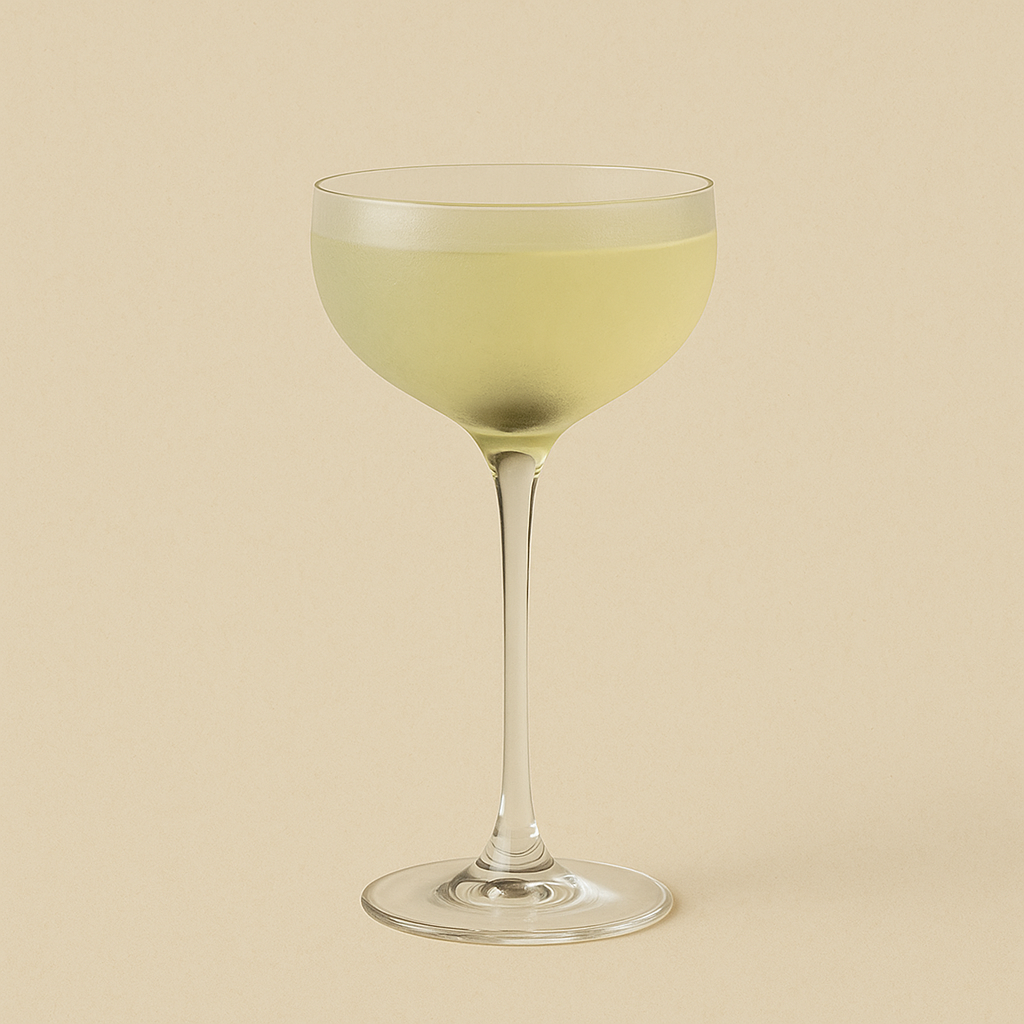 Front view of a pale yellow cocktail in a coupe glass showcasing a frosted bowl and long slender stem on a beige background