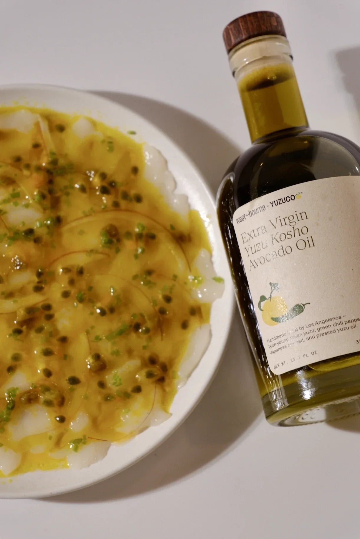 scallop carpaccio with passionfruit and yuzu dressing on a white plate