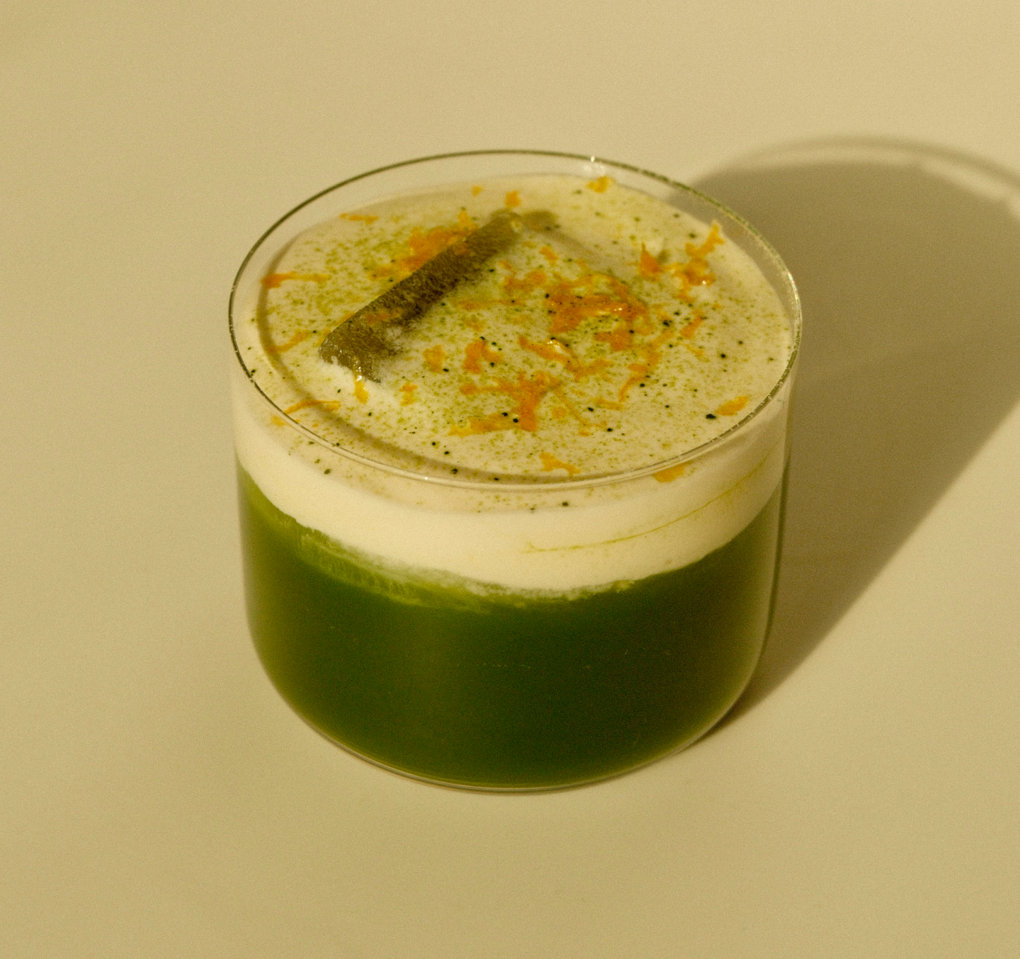 close up shot of yuzu latte with cream on top, one large ice cube