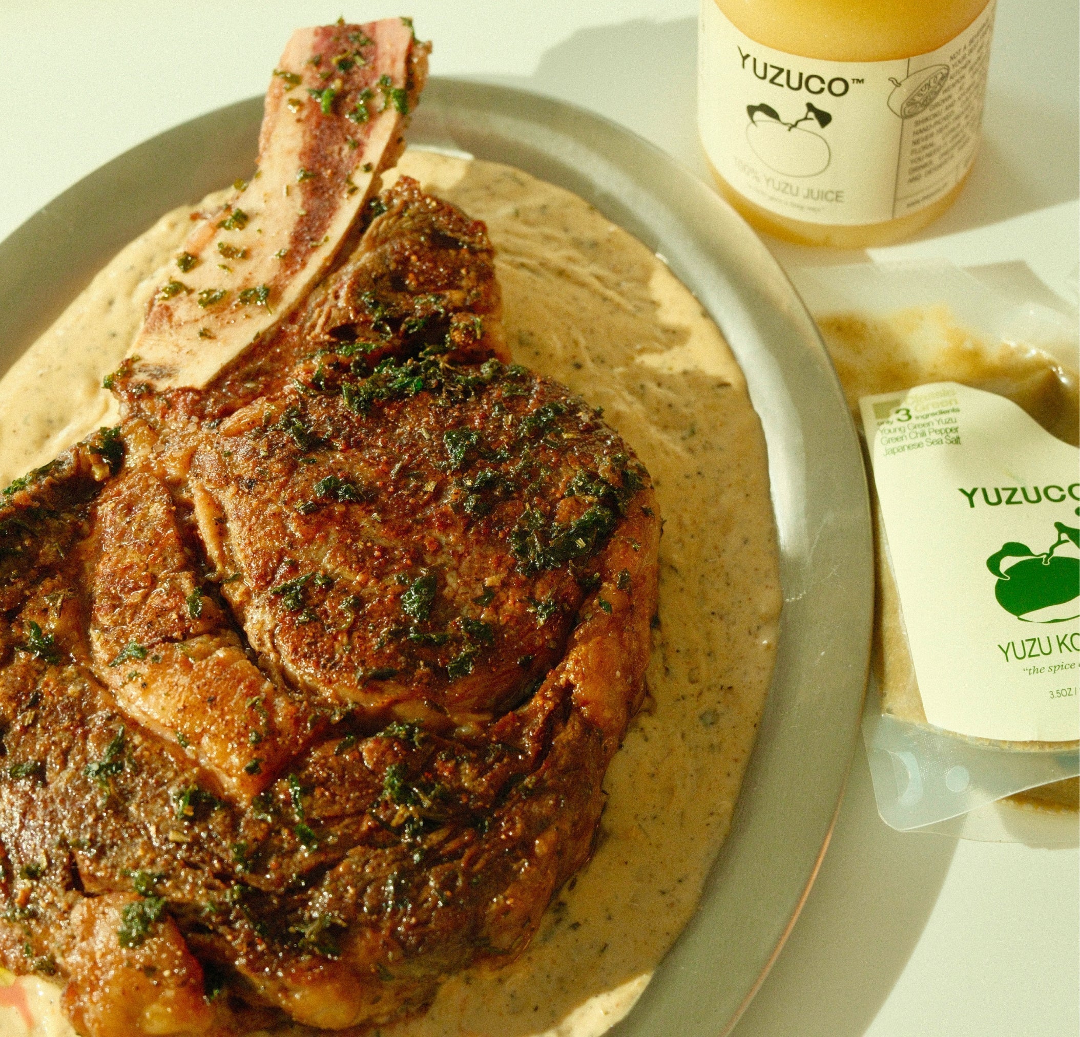 ribeye steak on top of a silver platter of yuzu kosher peppercorn sauce