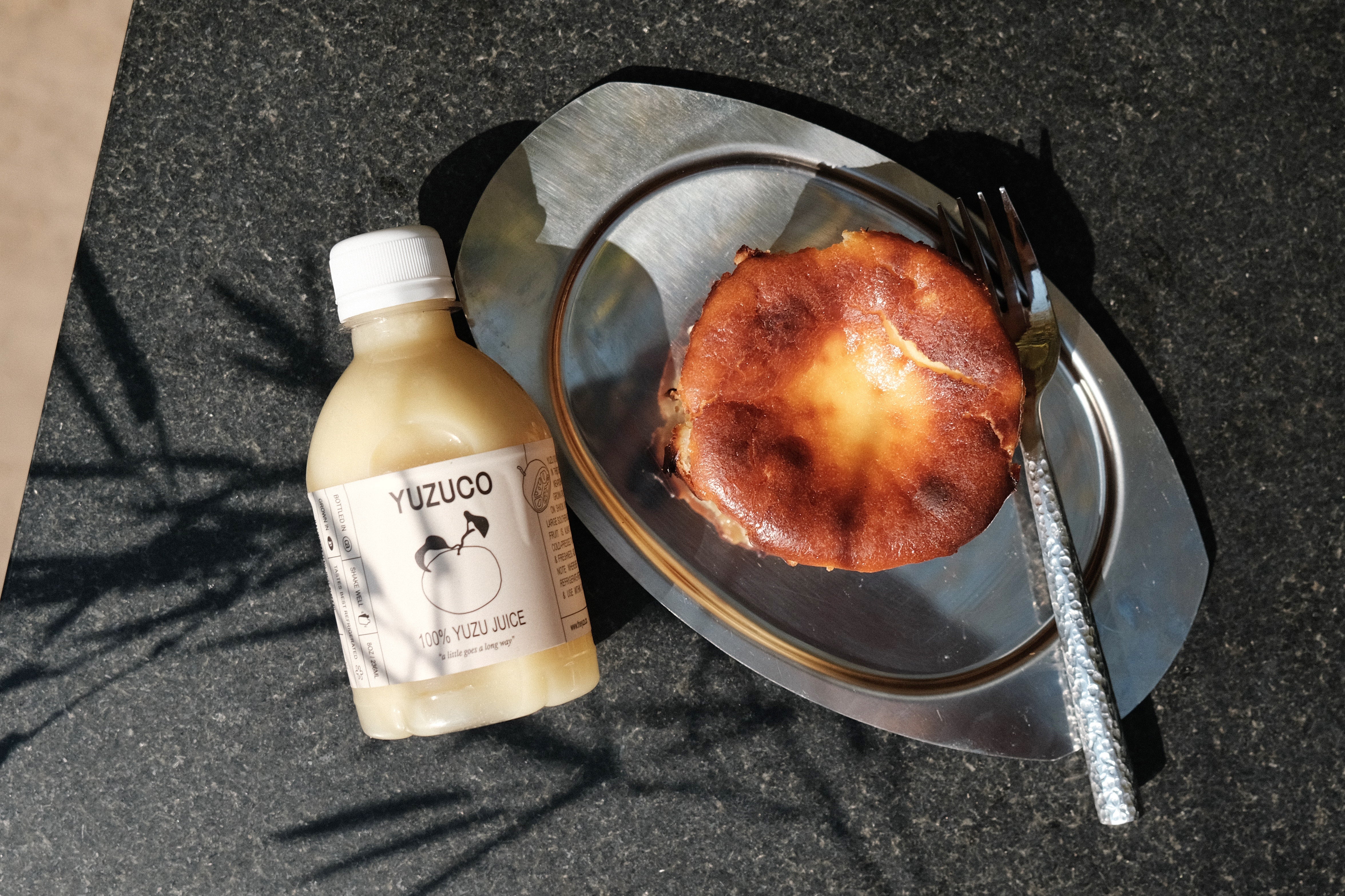 bruleed yuzu basque cheesecake on a silver platter with a spoon