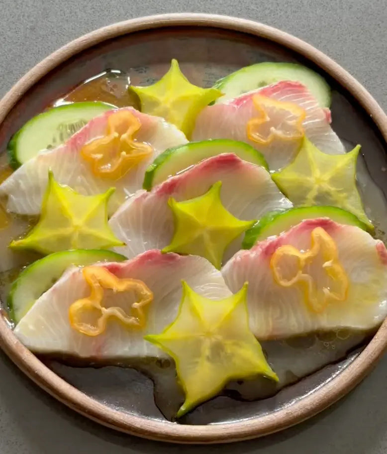 hamachi star fruit crudo on a brown plate with soy yuzu vinaigrette
