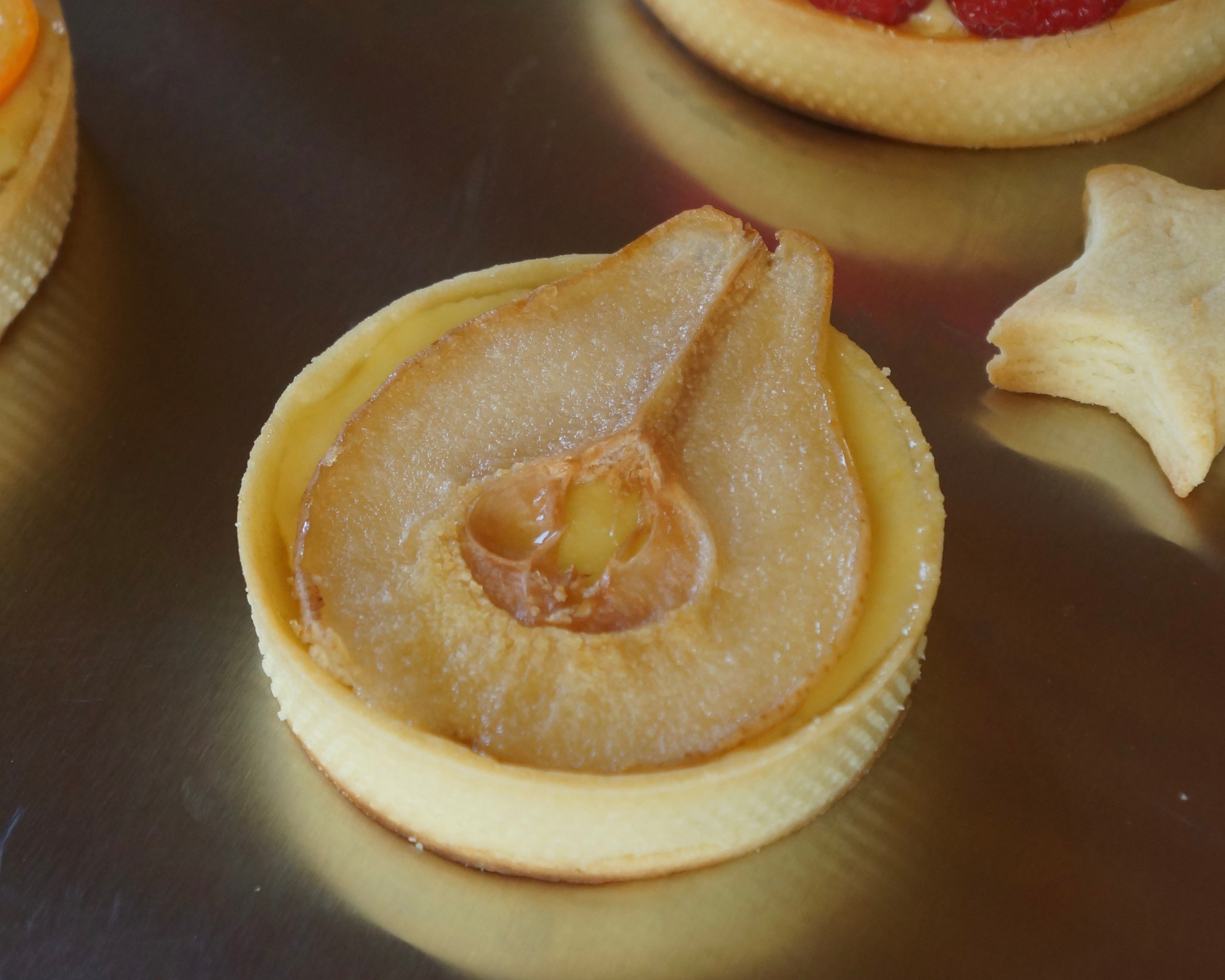 pear tart on top of aluminum sheet with star cookie in background