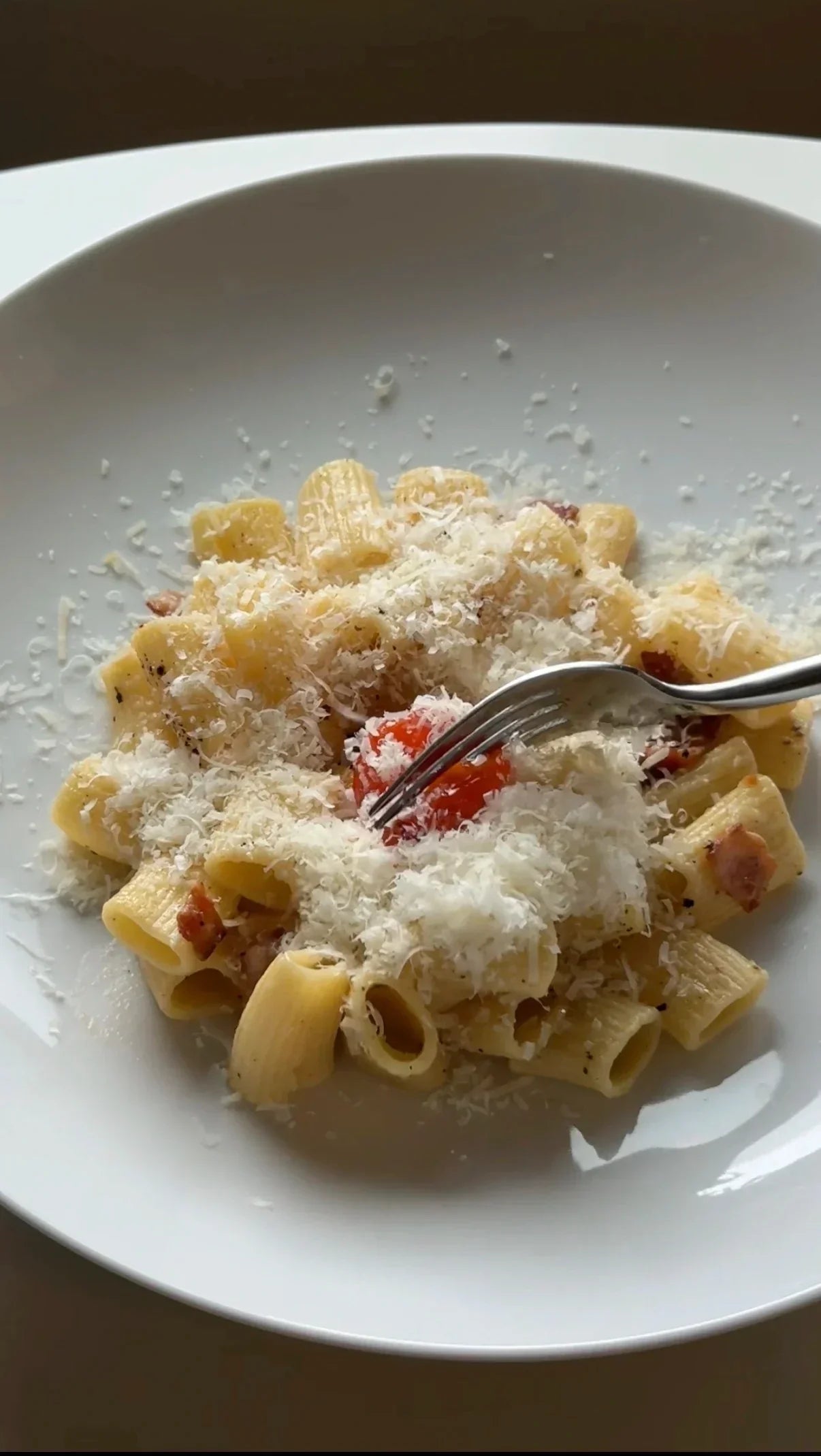 top view of yuzu carbonara with soy cured egg yolk in a white plate