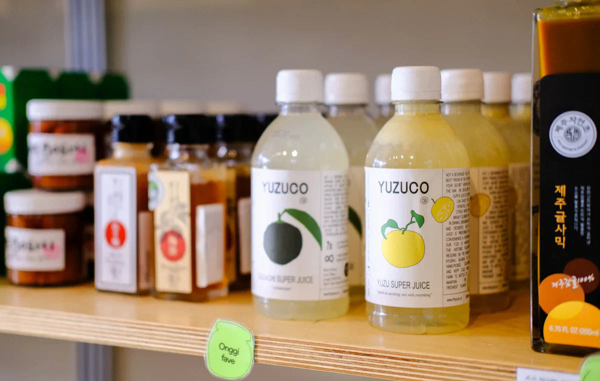 Bottles of Yuzuco cold-pressed yuzu juice and Yuzu Super Juice displayed on a retail shelf in New York City.