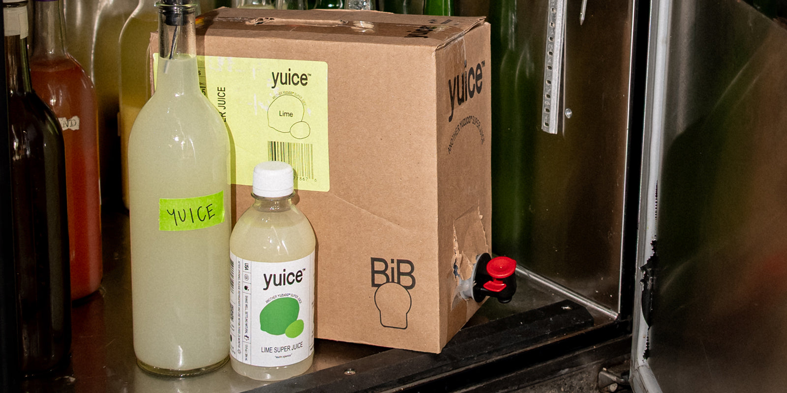 Yuice products: glass bottle, plastic bottle, and bag-in-box with tap on stainless-steel shelf