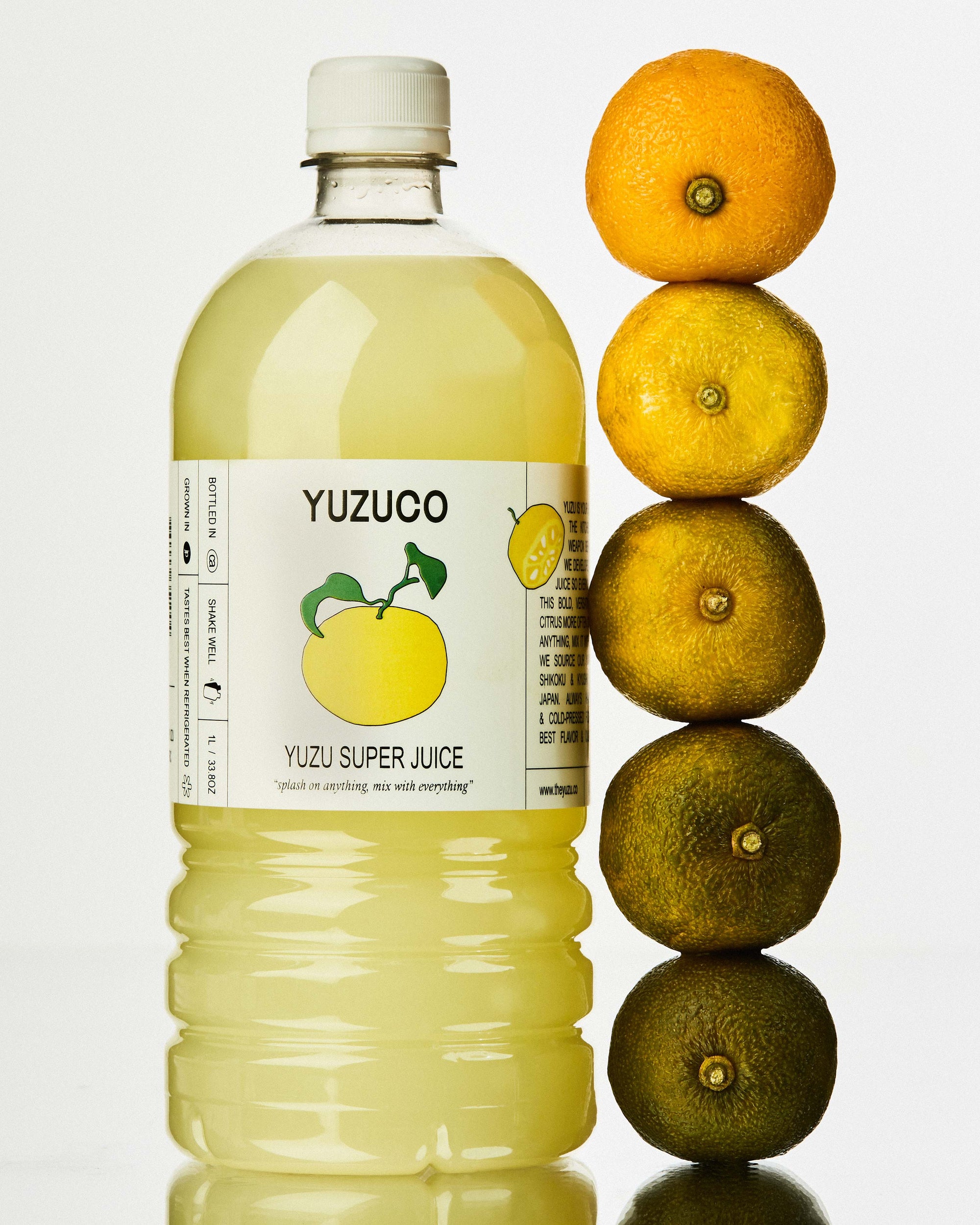 yuzuco yuzu super juice next to yuzu fruit at different stages of ripeness