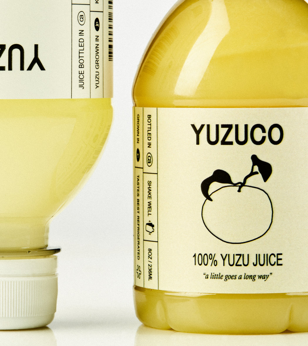 Close-up front view of Yuzu Duo two-bottle set showcasing YUZUCO label and 100 percent Yuzu Juice text on a white background