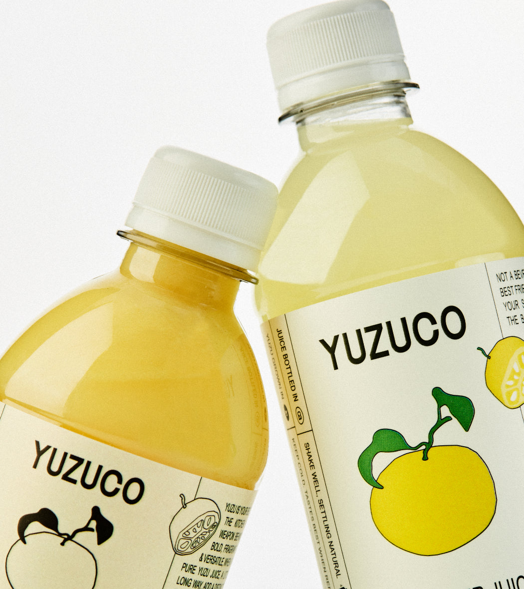 Close-up front view of Yuzu Duo two-bottle set showcasing YUZUCO labels and yellow yuzu illustrations on white background